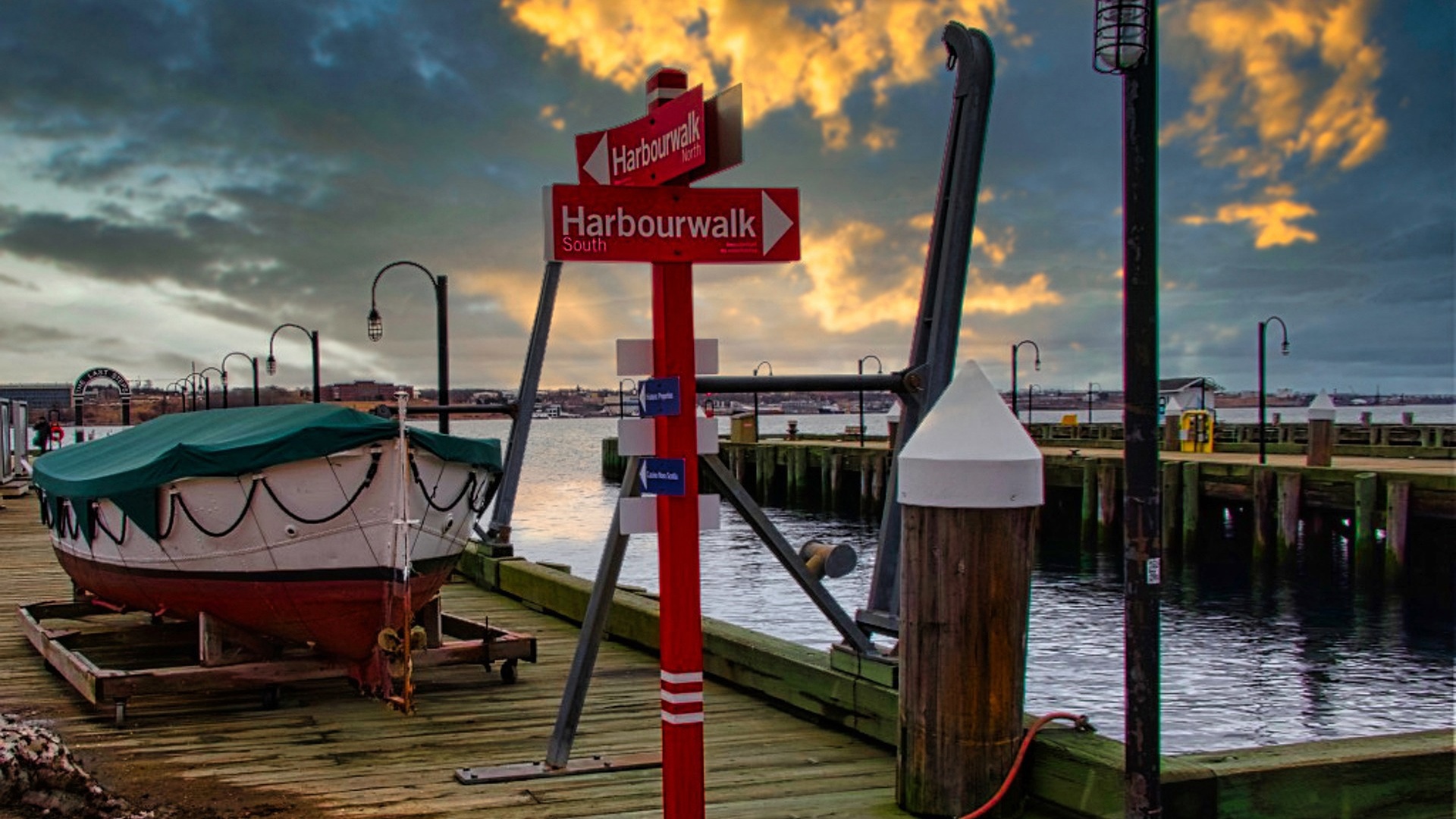 Halifax, Nova Scotia: a boat on a wooden pier with a Harbourwalk sign at sunset